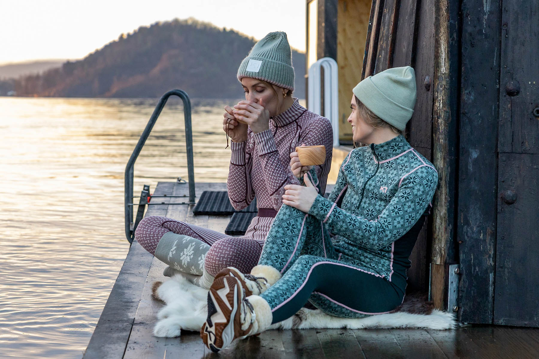 women sitting by the lake in kari traa wool base layers