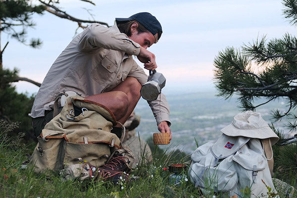 man pouring coffee in the woods while wearing amundsen sports outdoor wear