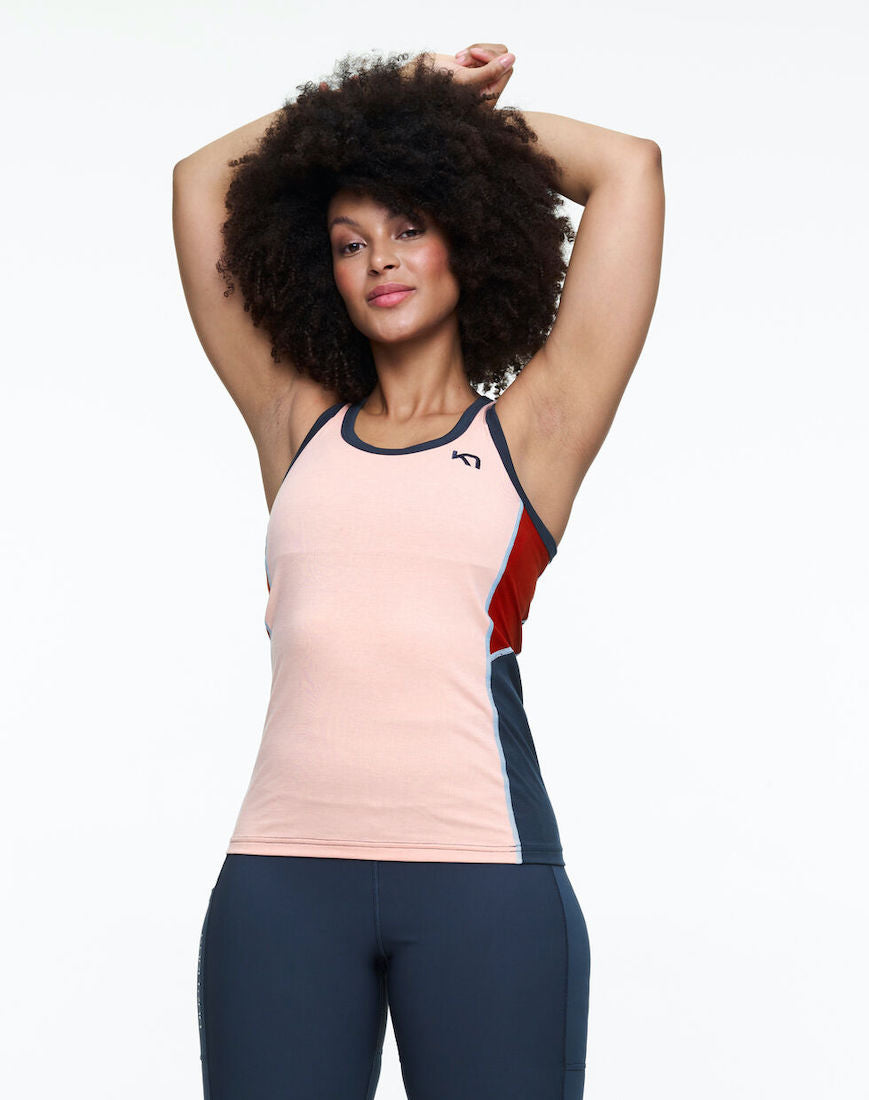 Front view of model wearing multi colored hiking tank top in pink color scheme.