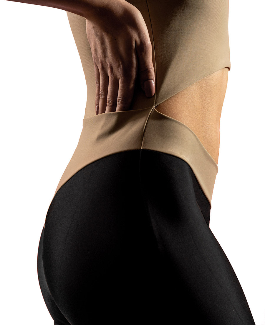 Side view of woman wearing sand VanillaShanti one-piece yoga bodysuit or unitard