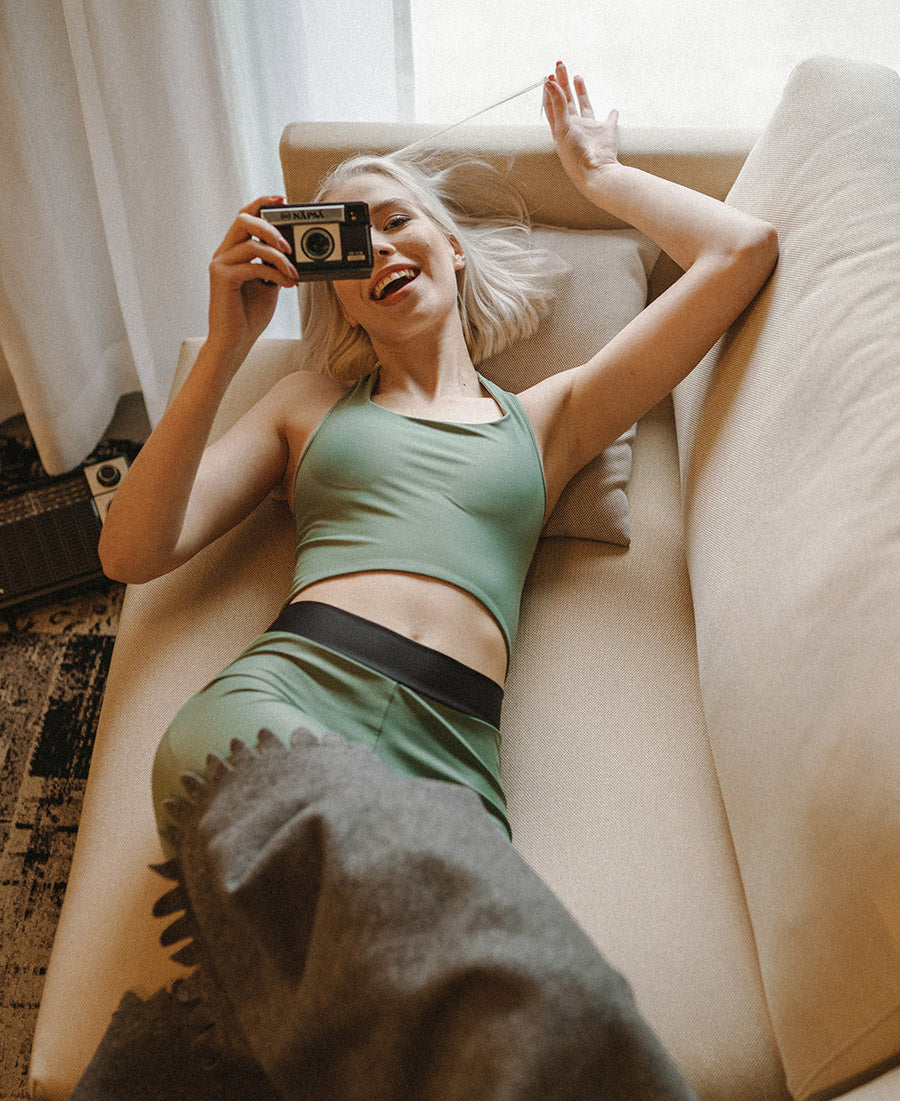 Worm's eye view of woman wearing olive greenVanillaShanti one-piece yoga bodysuit or unitard